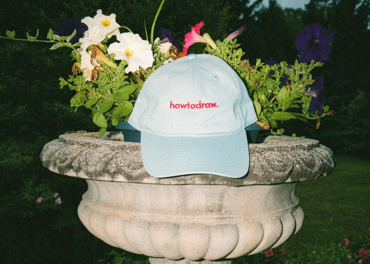 Light blue cap with red text on a stone urn with flowers outdoors